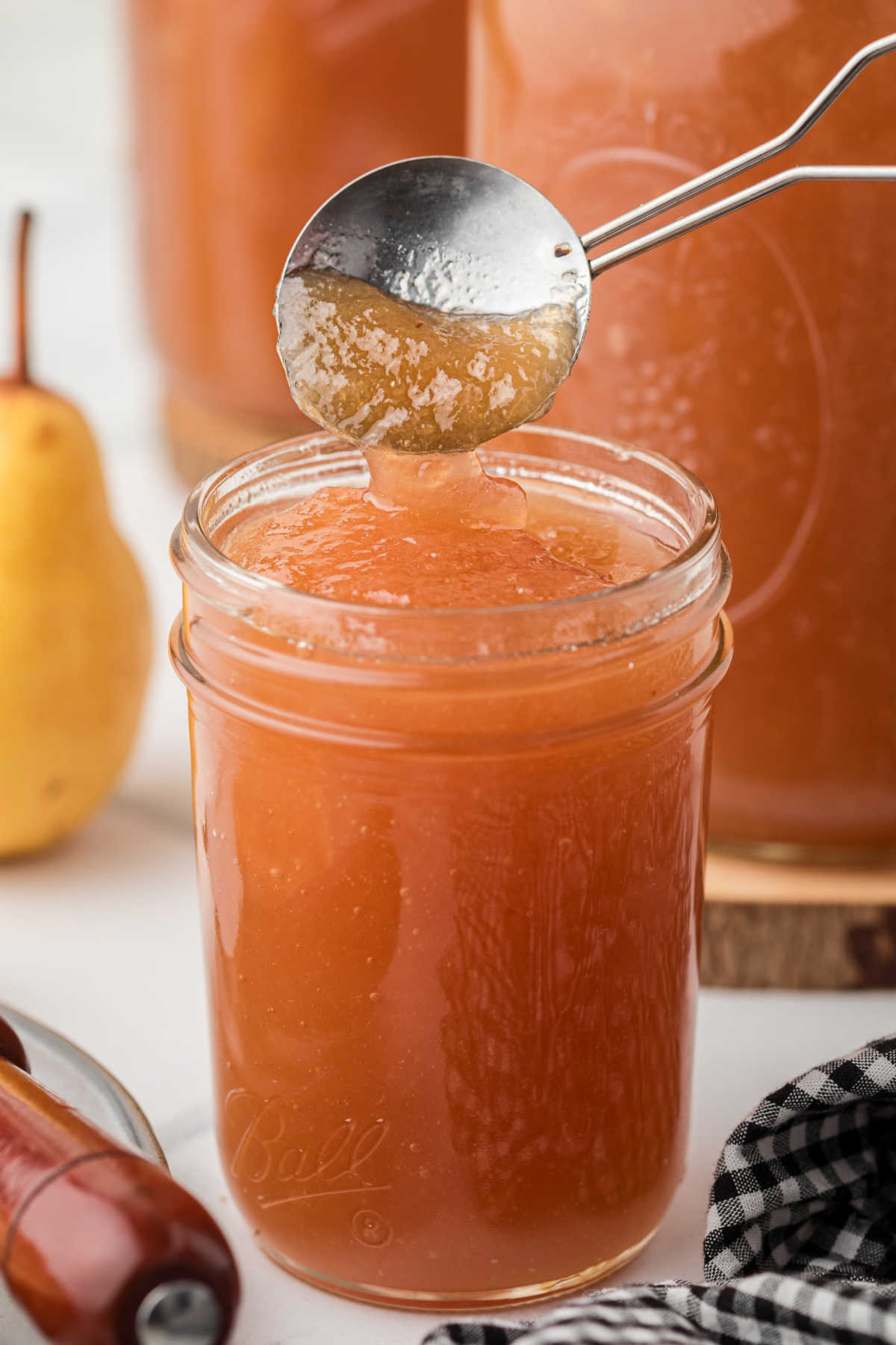 A jar of Amish Pear Honey with a spoon dipping in.