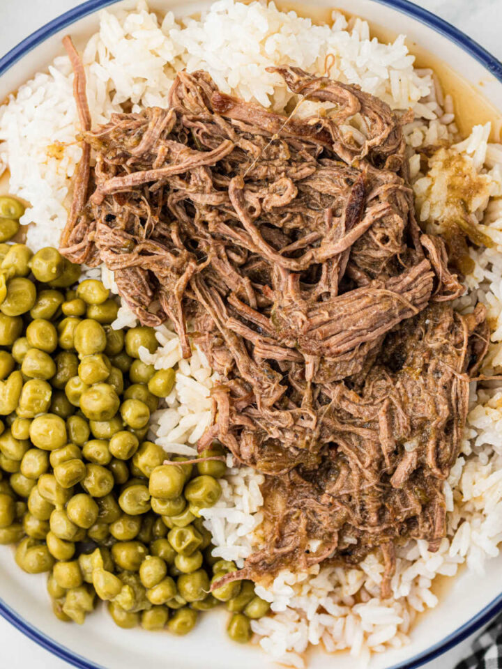 Overhead view of a plate full of Cajun rice and gravy with some peas.