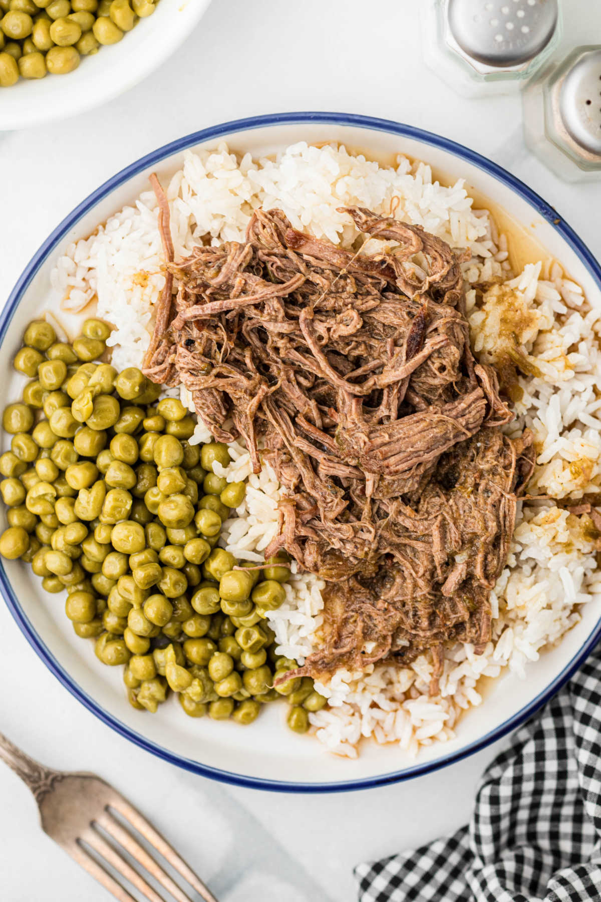 An overhead shot of a plate full of Cajun rice and gravy with green peas.