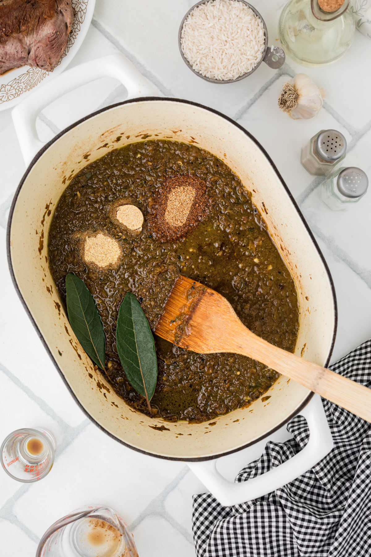 Seasonings and bay leaves added to a Dutch oven with a gravy.