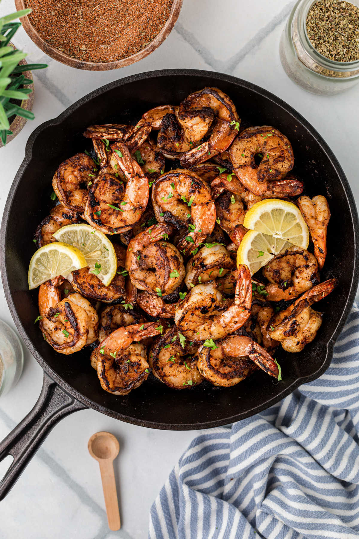 Overhead shot of a black skillet filled with Cajun blackened shrimp, with a few lemon slices.