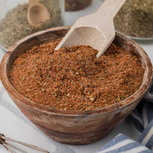 A small wooden bowl of blackened seasoning with a small scooping spoon.