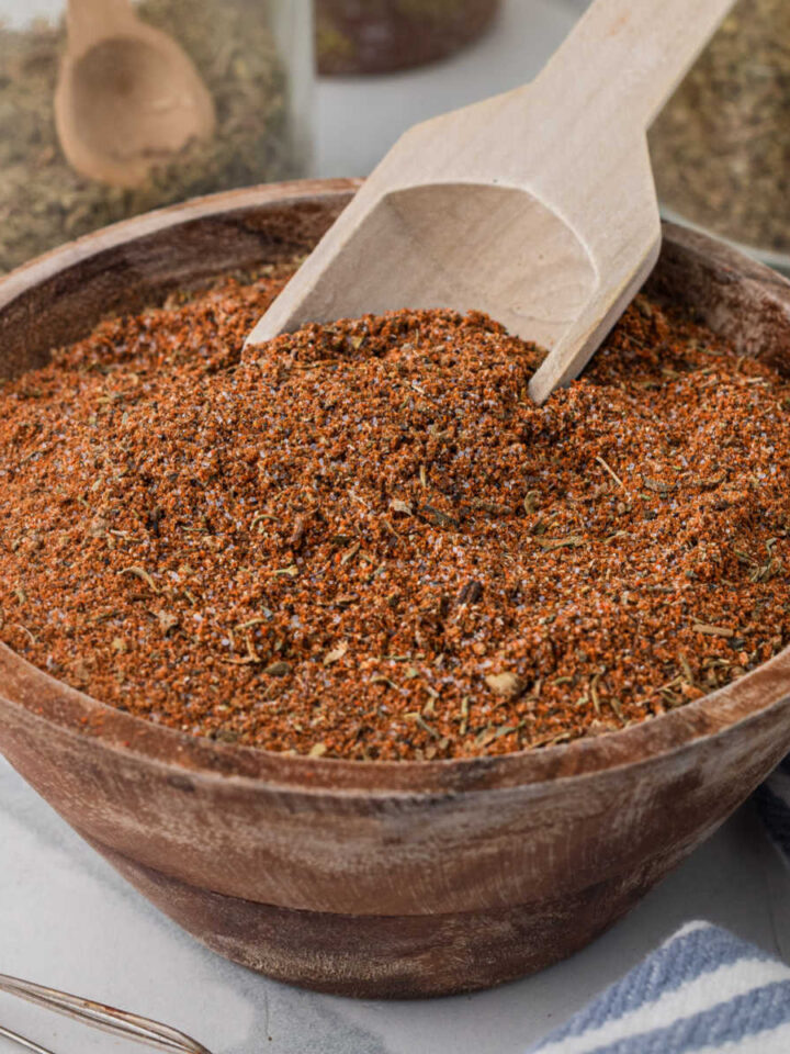 A small wooden bowl of blackened seasoning with a small scooping spoon.