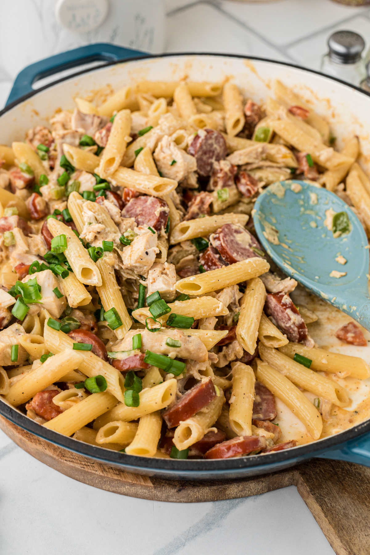 A side shot of a skillet filled with chicken and sausage noodles.