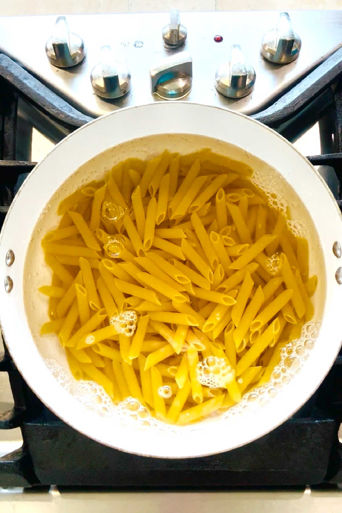 A pot of penne pasta cooking on the stove.