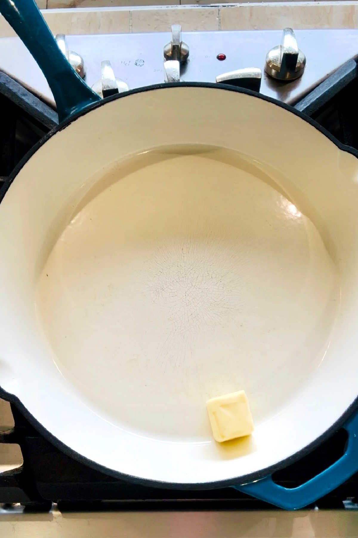 A large white skillet with a knob of butter.