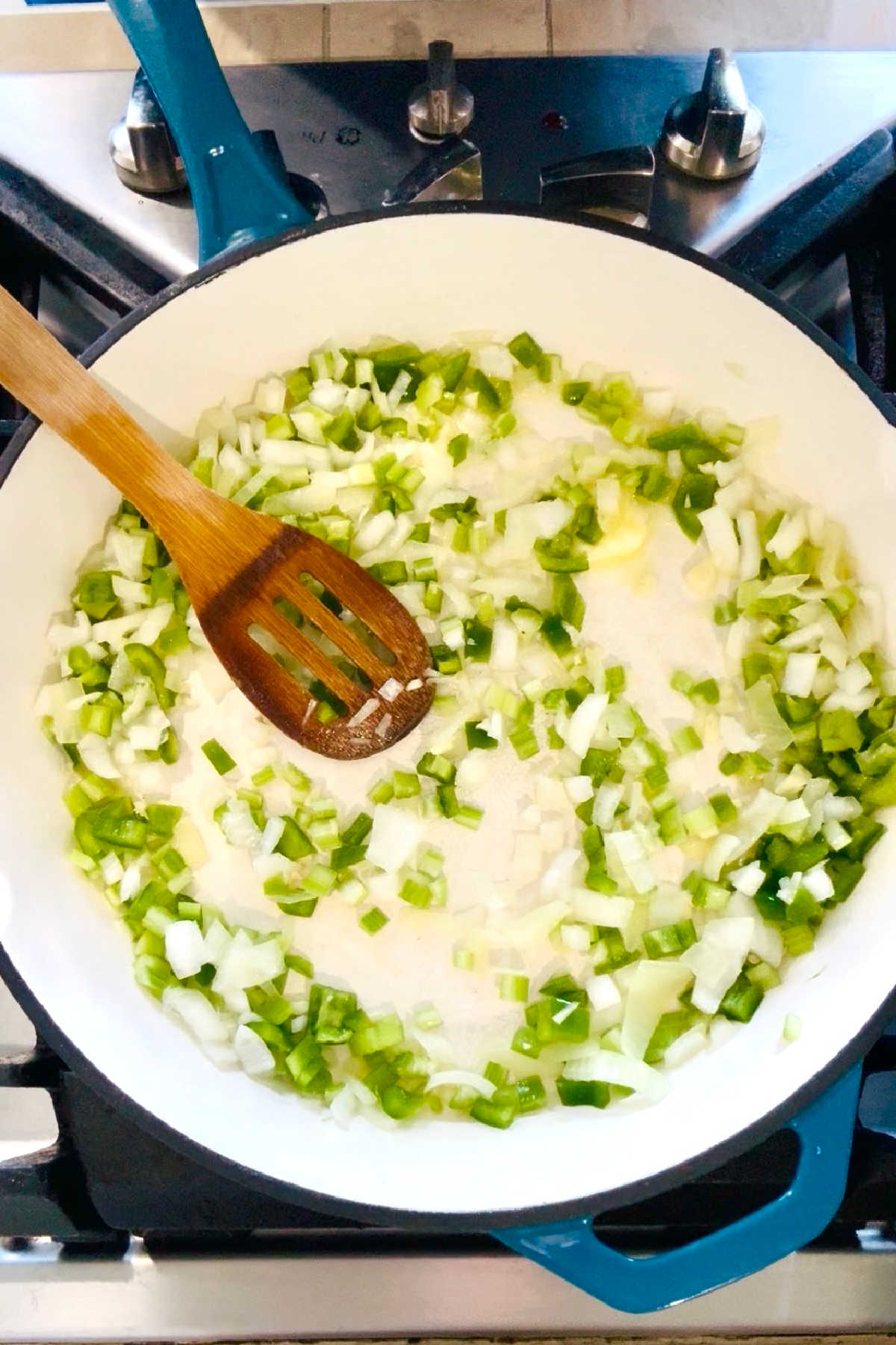 The holy trinity of onions, bell peppers and celery added to a large skillet.