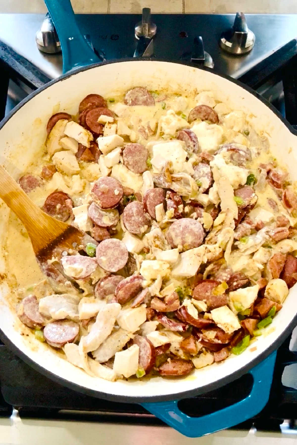 A large skillet with smoked sausage and chicken.