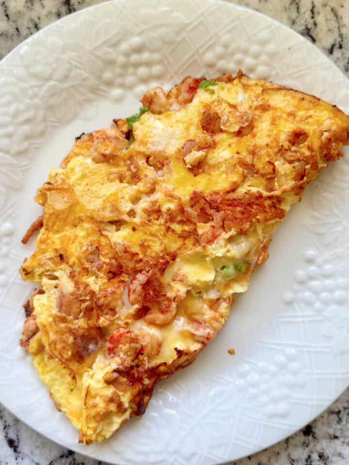 A delicious looking crawfish omelette on a white plate.