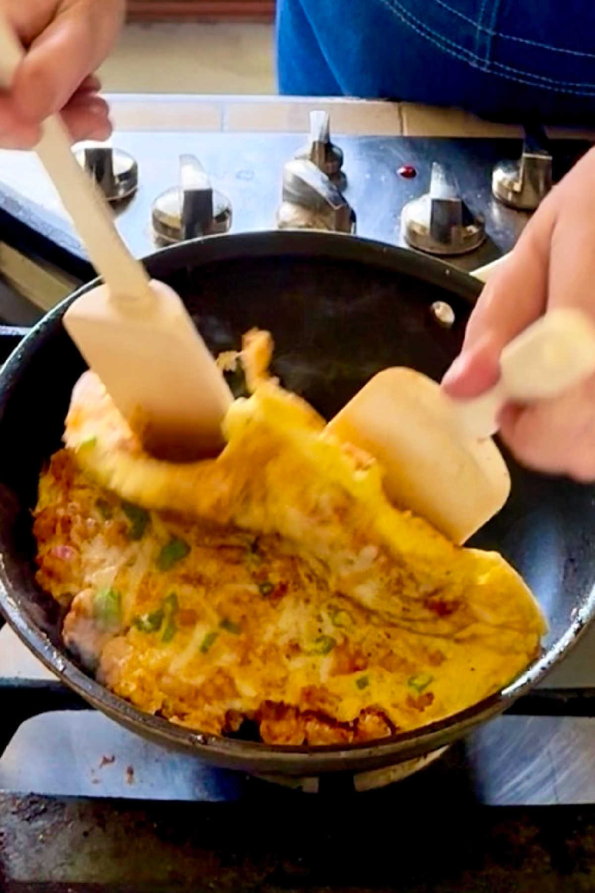 An omelette being folded in half with two spatulas.