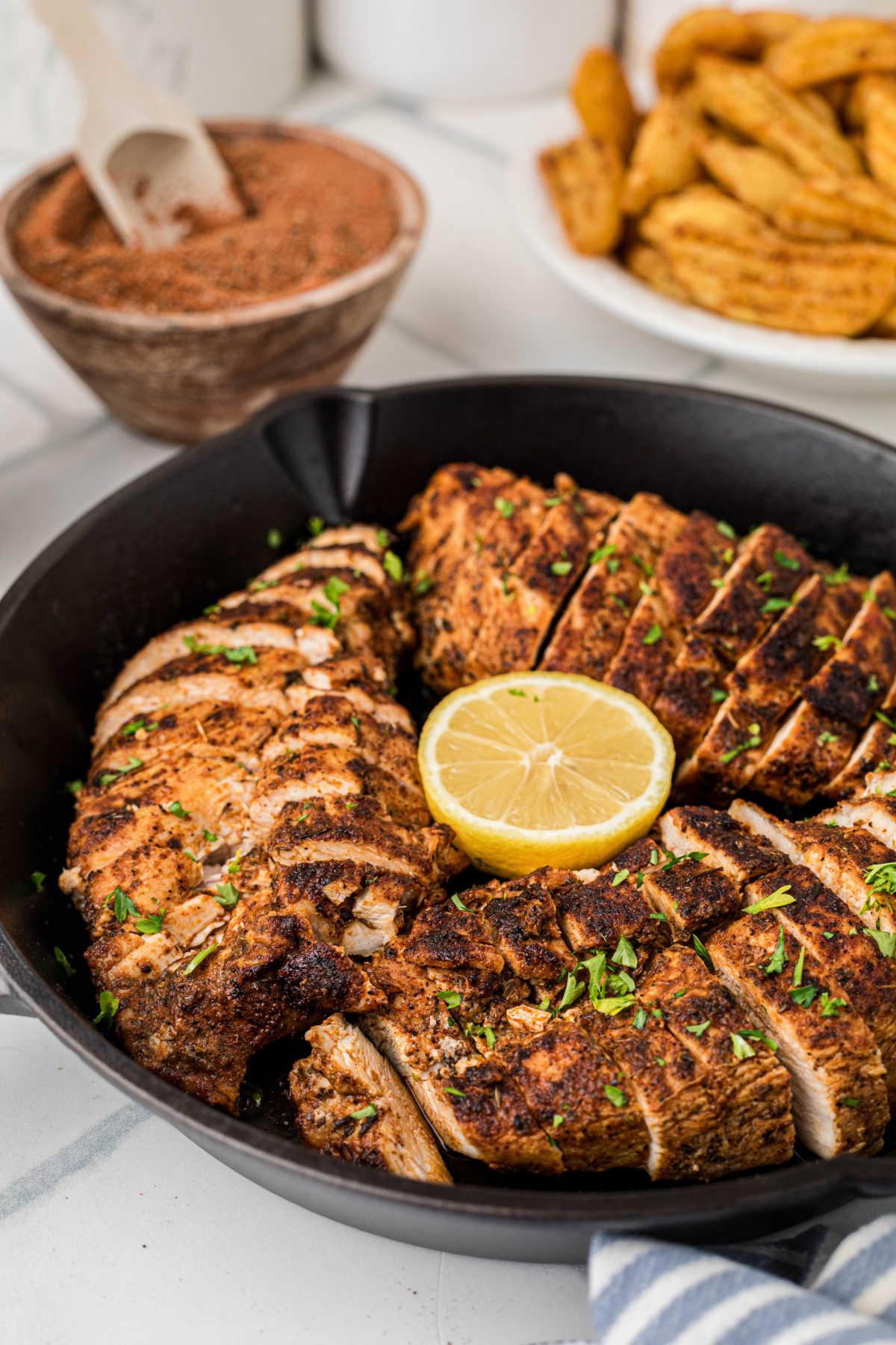 Side shot of a skillet with blackened chicken breasts, already sliced.