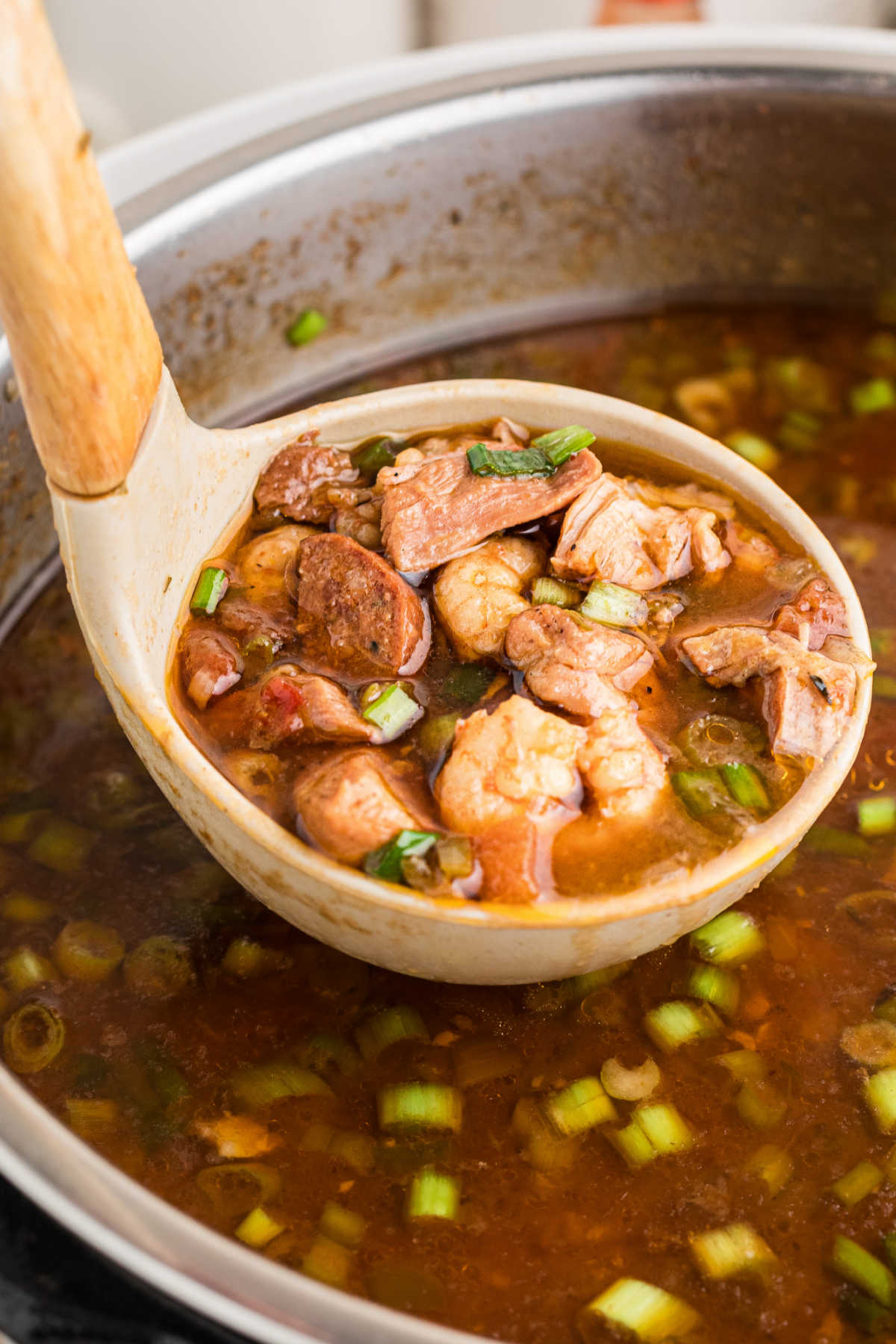 A close up shot of a ladle full of gumbo.
