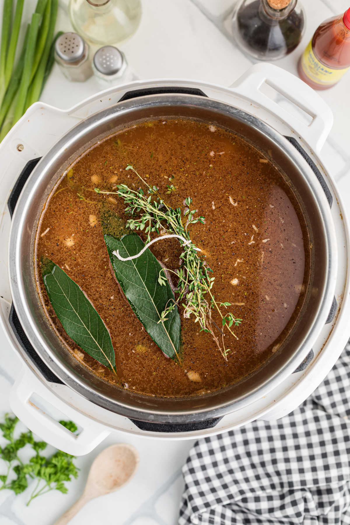 An instant pot filled with gumbo ingredients, and herbs.